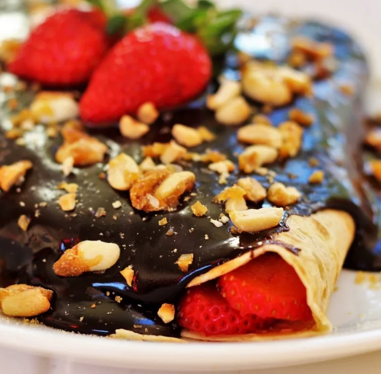 Crepe doce aberto com morangos, calda de chocolate e crocante